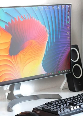 Kompjuterski monitor na belom stolu sa šarenom pozadinom